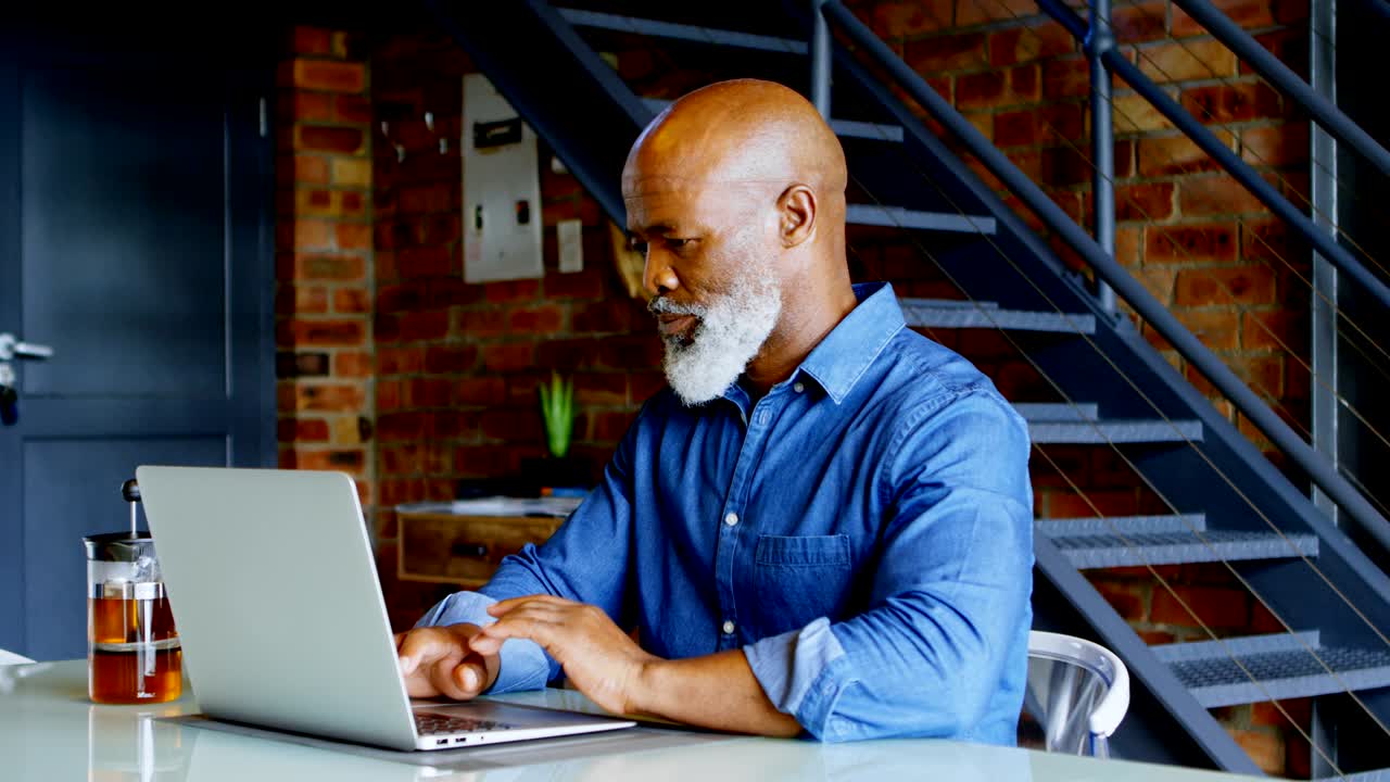 hombre mayor usando computadora portátil en la cocina en casa 4k