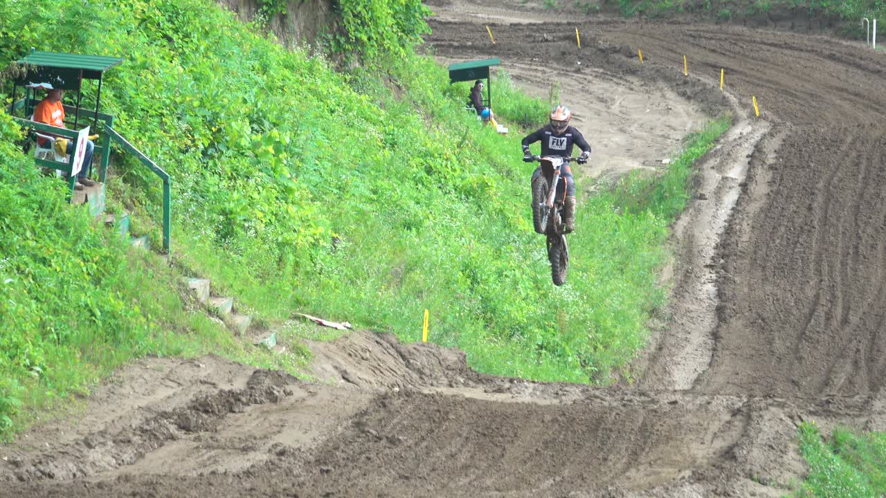 Un pilote de motocross saute et fait la course sur une piste de terre boueuse