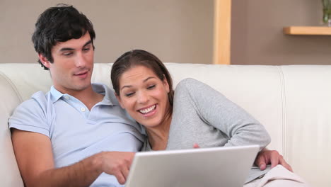 una pareja riendo frente a una computadora portátil