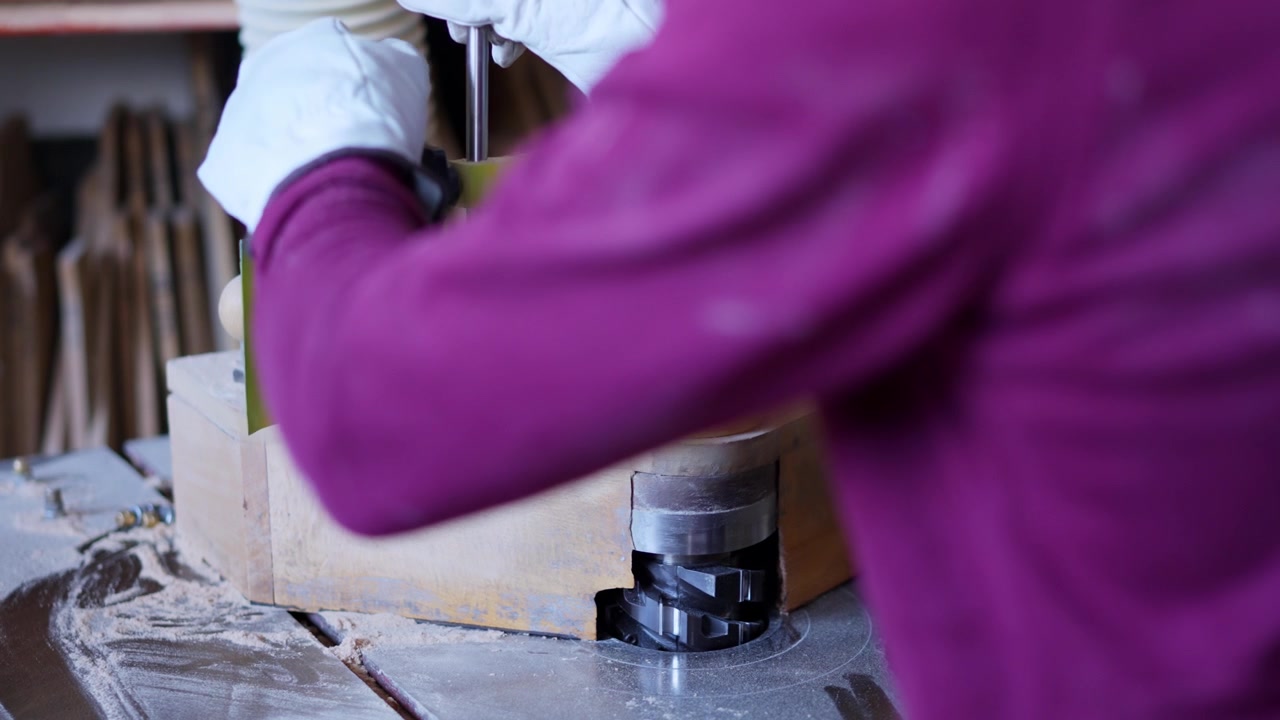 Worker shaping wood piece on edge banding machine
