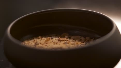 a bartender dip the glazed glass into crushed nuts to create a special crusta that garnishes the cocktail.