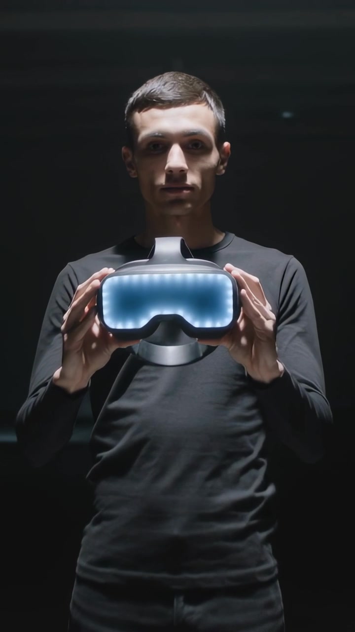 Vertical video: Lifting black-clad man, spotlight cueing, showing LED headset toward lens on stage
