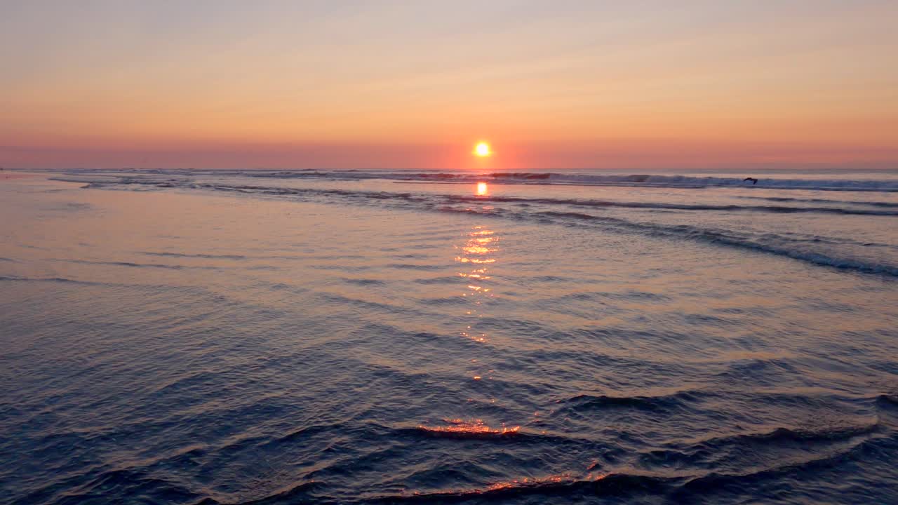 日の出時のビーチの穏やかな波