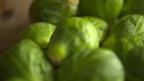 close up of a bunch of fresh, green brussel sprouts resting on a wood cutting board