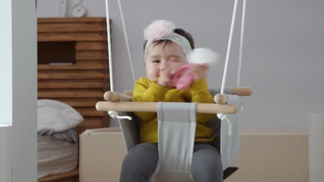 bebé en el columpio de la puerta, niño de un año jugando con un juguete mientras está sentado en el columpio de la puerta