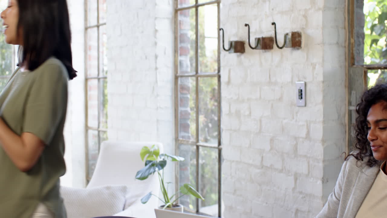 Woman standing by large windows at home, enjoying peaceful natural light
