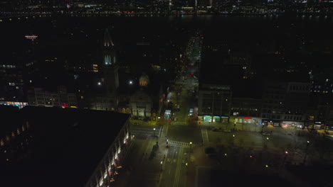 Forwards-fly-above-night-city.-Tilt-down-shot-of-road-intersection-with-crosswalks-in-urban-borough.-Boston,-USA