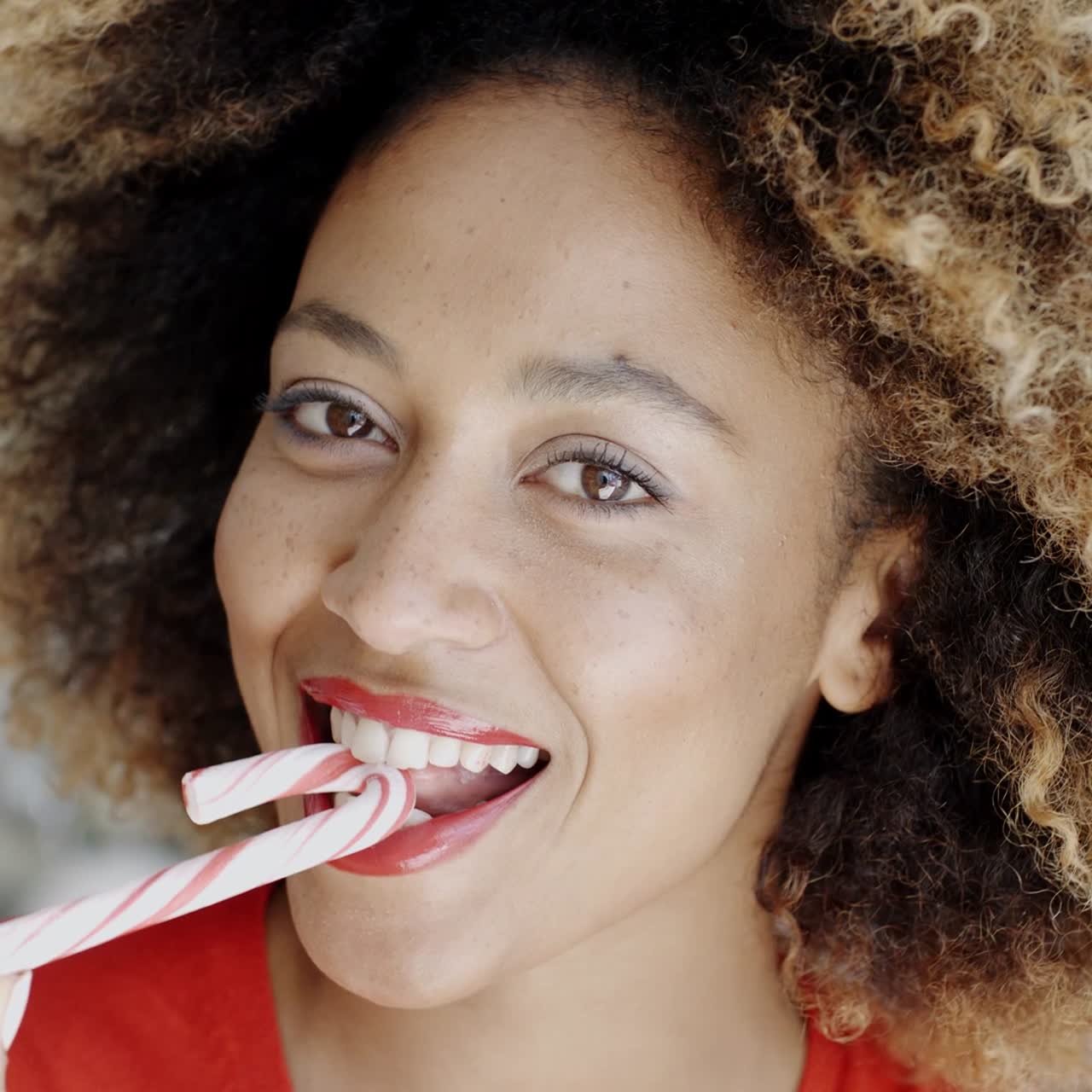 mujer joven mordiendo un bastón de caramelo festivo