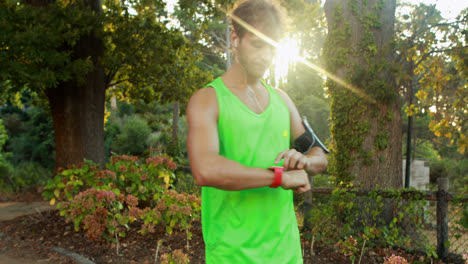 man checking his smartwatch while jogging in park