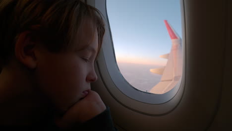 niño cansado mirando por la ventana del avión