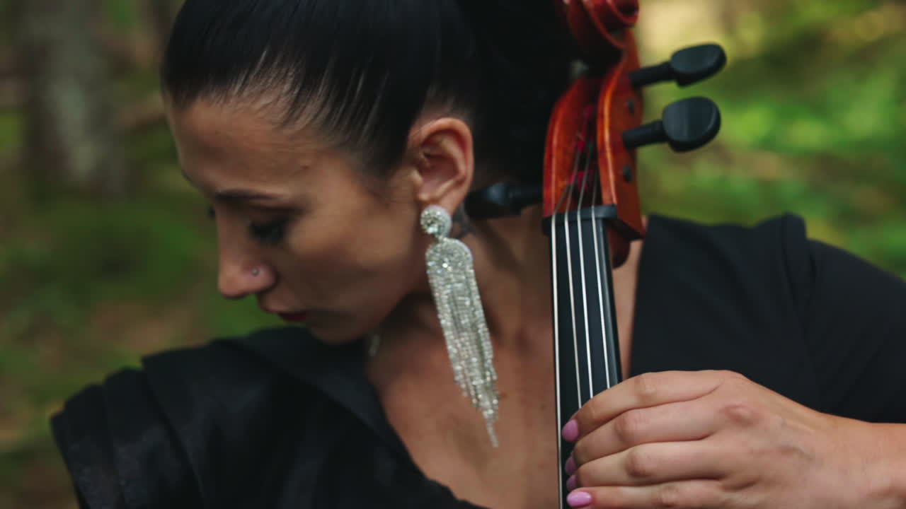 Female musician performs music outdoors. Portrait of a woman with luxury earrings playing the musical instrument. Close-up.