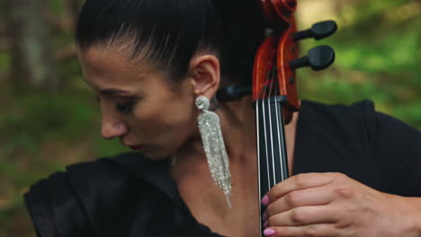 female musician performs music outdoors. portrait of a woman with luxury earrings playing the musical instrument. close-up.