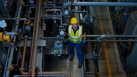 industrial worker inspecting machinery and pipes