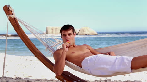 attractive man eating ice lolly in a hammock