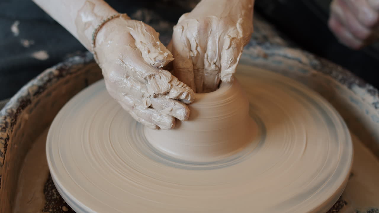 manos moldeando arcilla en una rueda de cerámica