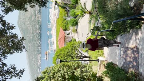 a young woman dressed in a red shirt with dotted pants is walking down the stairs to the sea