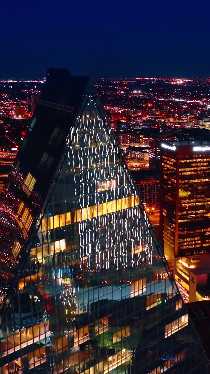 Drone in ascesa nel centro della luminosa Dallas. Paesaggio metropolitano americano di notte. Video verticale.