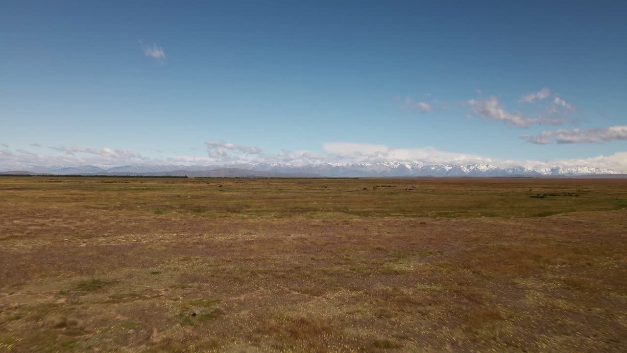 Expansive, dry prairie plains with picturesque mountain range in distance
