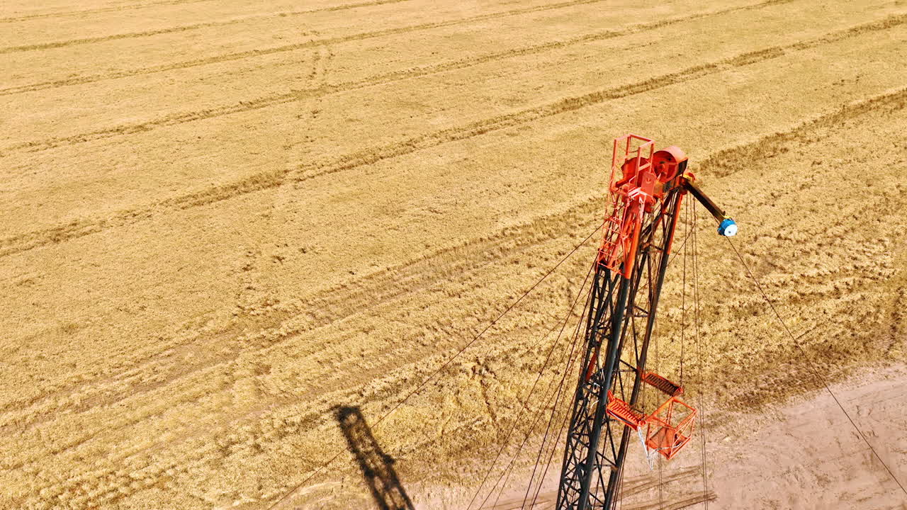 Descending above the truck with derrick for oil drilling. Top view. Agricultural field with dry wheat at backdrop.