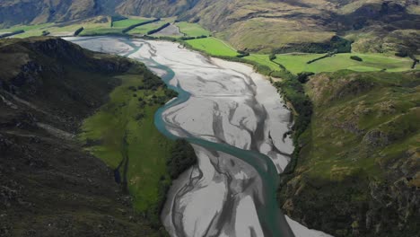 Aerial-of-Matukituki-River,-tilt-up-to-high-mountain-scenery,-New-Zealand