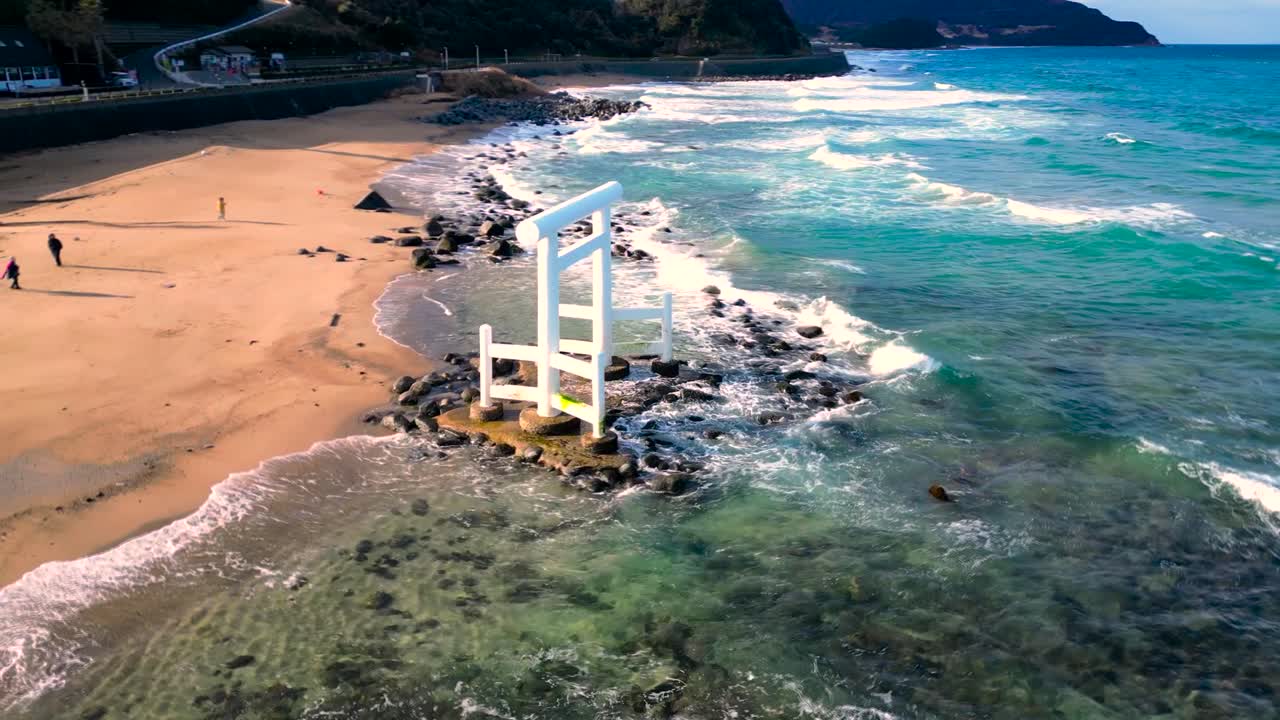 Drone orbitando um portão torii à beira-mar.