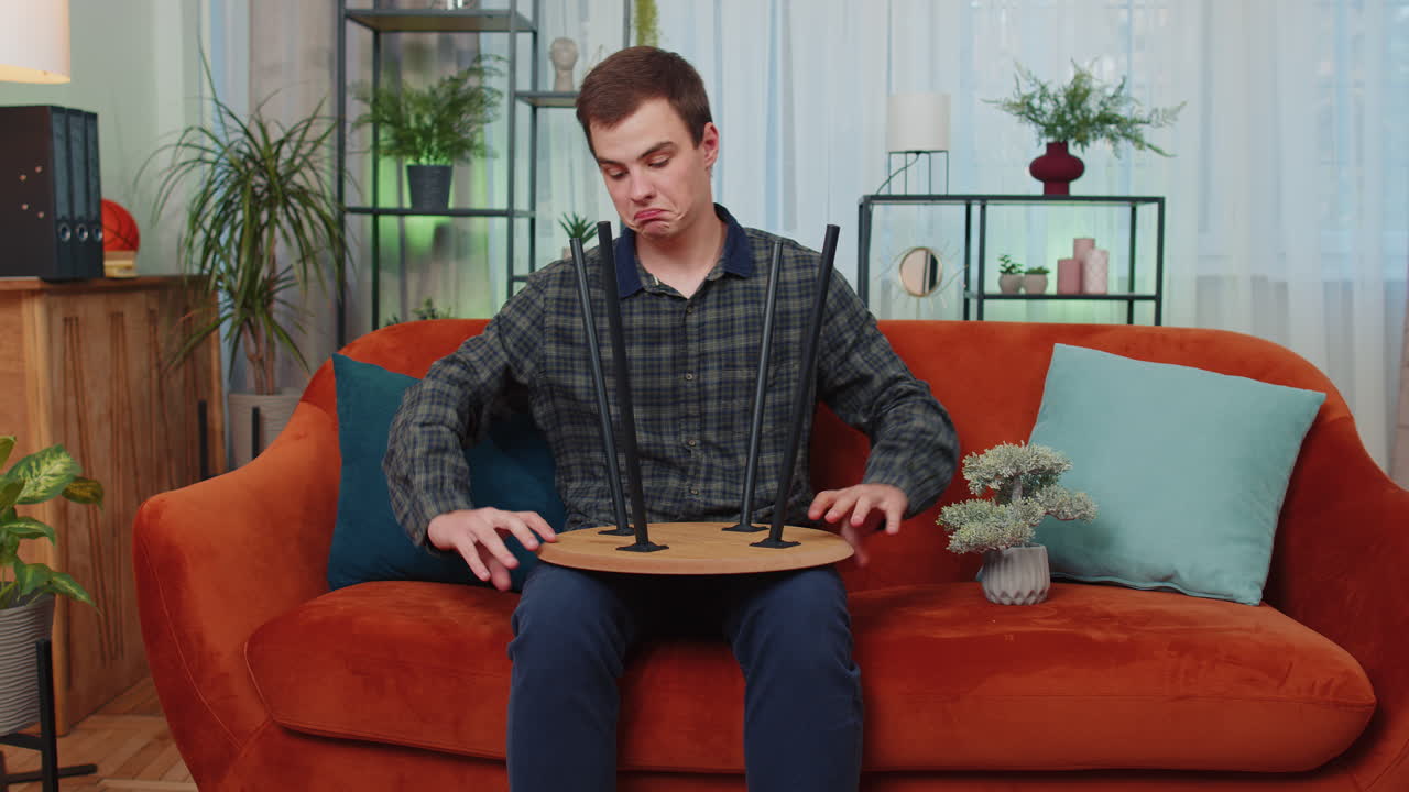 남자가 새로운 아파트에서 집에 가구를 조립하고, 성공적인 테이블을 수집하고, 수리하고, 고정합니다.