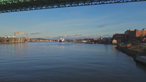 Drone-Flying-Under-Alvsborgsbron-Bridge-With-Eriksberg's-Crane-In-The-Distance-At-Gothenburg,-Sweden