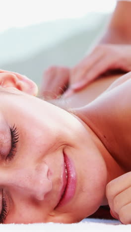 smiling brunette enjoying a massage poolside