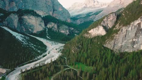 Forward-tilt-up-aerial-shot-in-the-Alps-of-a-valley-next-to-rocky-cliffs