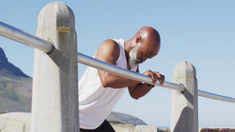 senior african american man exercising stretching on rocks by the sea