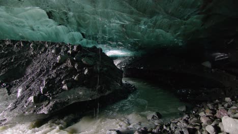 on the edge of a blue ice cave of the glacier with a small cold stream in iceland