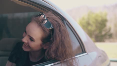 joyful woman looks out of car talks to friend in afternoon