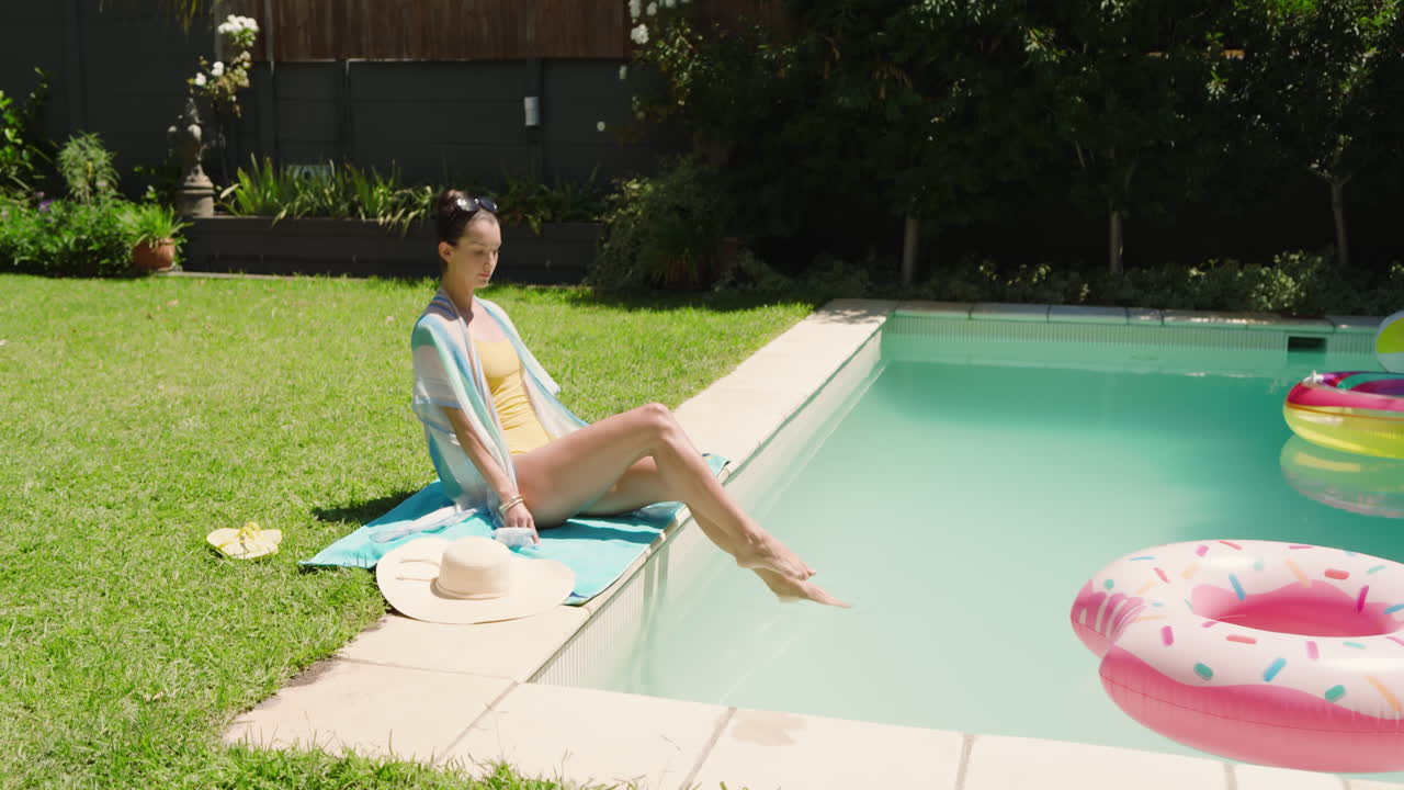 Relaxing by pool, woman in sunglasses dipping feet, enjoying sunny day