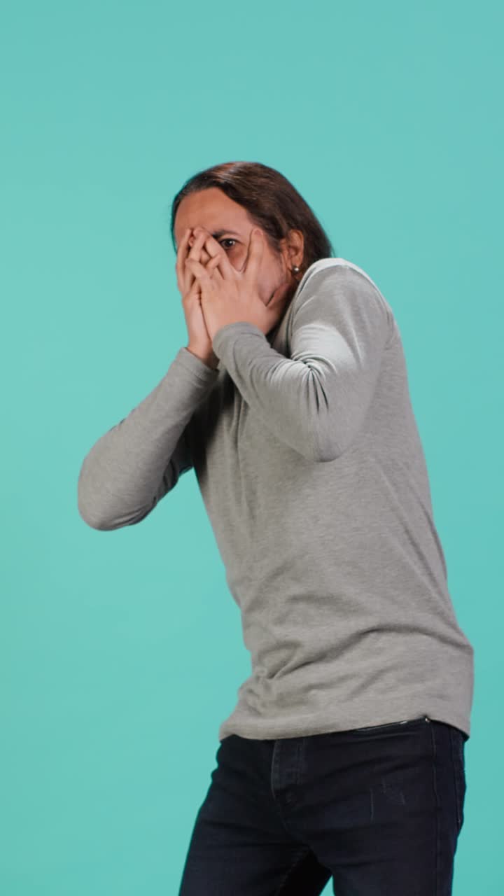 Vertical video Portrait of frightened man covering his face with hands, feeling distraught