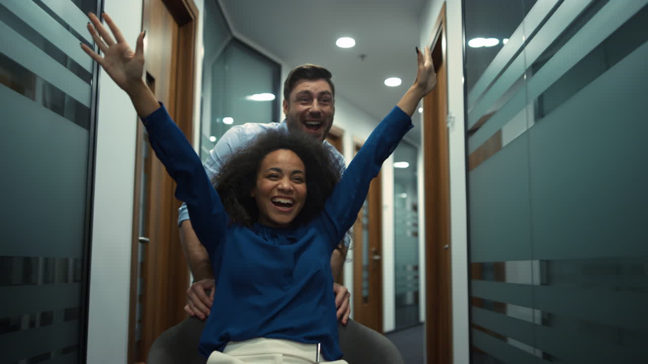 equipo de negocios multiétnico celebrando el éxito en la compañía. carrera de sillas de oficina.