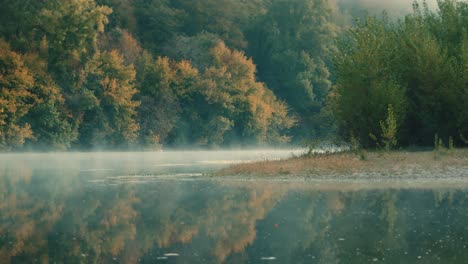 small river with mist above the water, with autumn colors in the trees, beautiful reflections in the water. dordogne, france