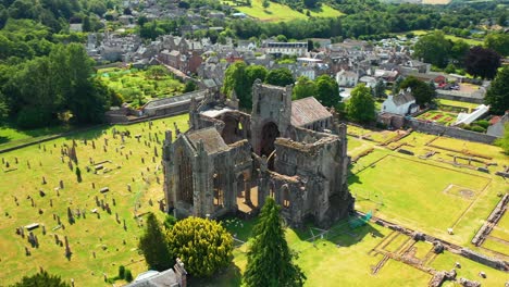 Close-up-aerial-of-Scottish-landmark-Melrose-Abbey-with-songbirds-flying-around