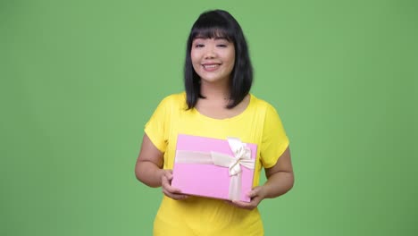 beautiful happy asian woman thinking while holding gift box