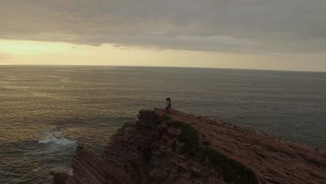 loving couple kissing on rocky cliff near sea