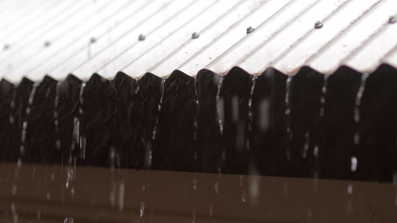 Rain pouring off corrugated tin roof during thunderstorm