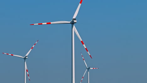 wind turbines for renewable energy. wind turbines with red and white blades stand against a clear blue sky, capturing wind energy in a rural landscape