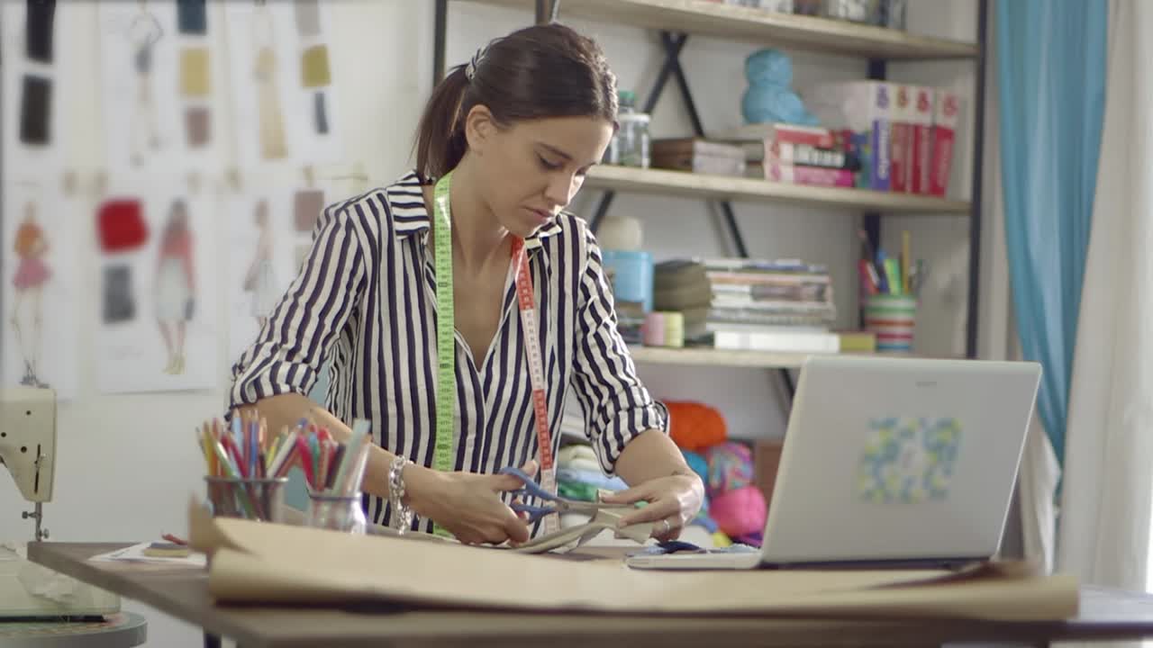 Diseñadora de moda cortando tela en su estudio creativo