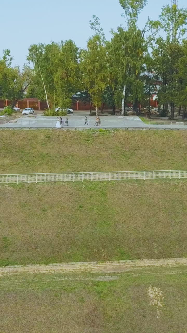 distant newlywed couple on park ground near cascade hill with modern long steps on nice autumn day bird eye view