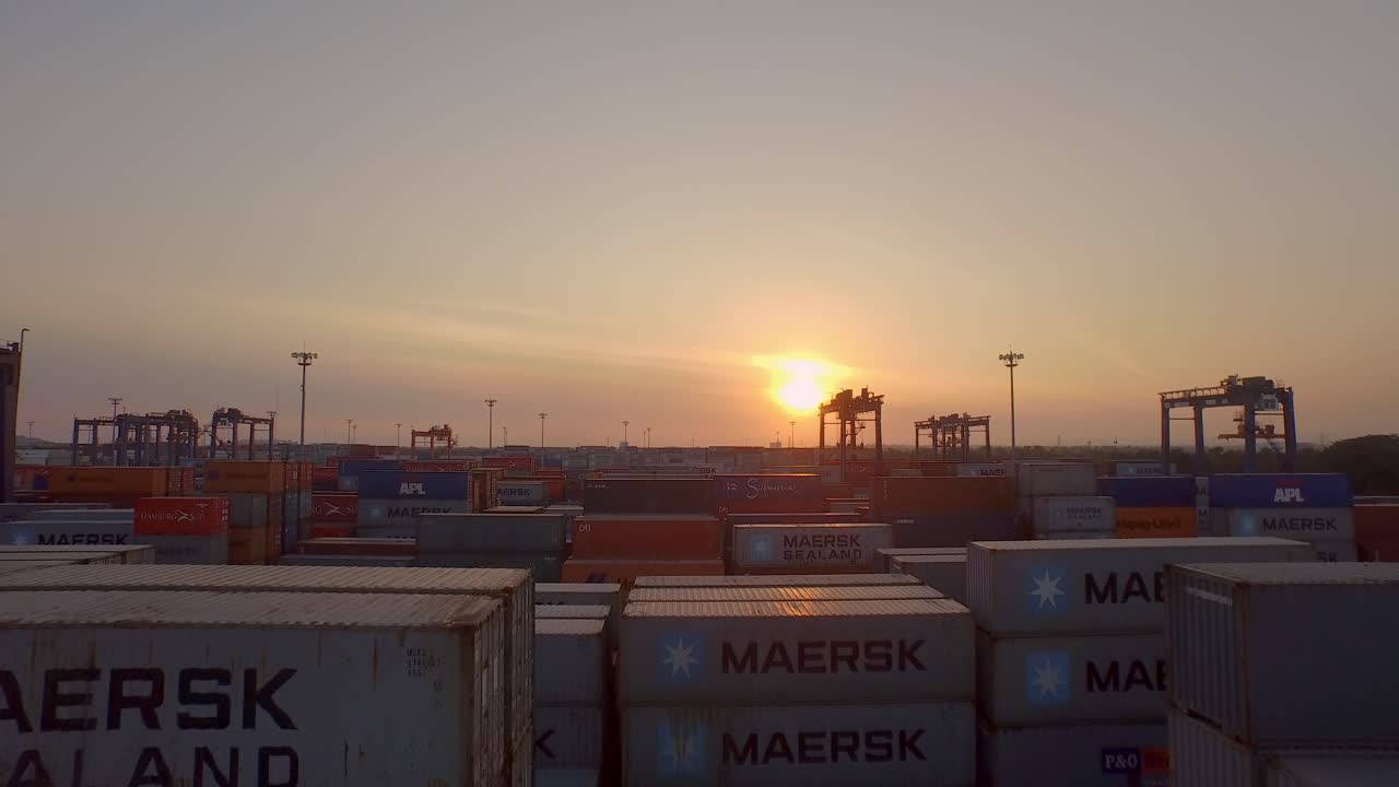 Aerial shot revealing the sun behind containers in a port