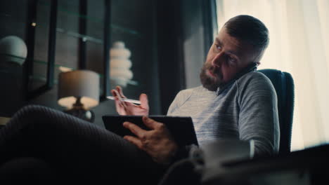 professional stock exchange broker having phone call, monitoring real-time stocks and exchange market charts using tablet computer. successful investment agent working in office of financial agency.