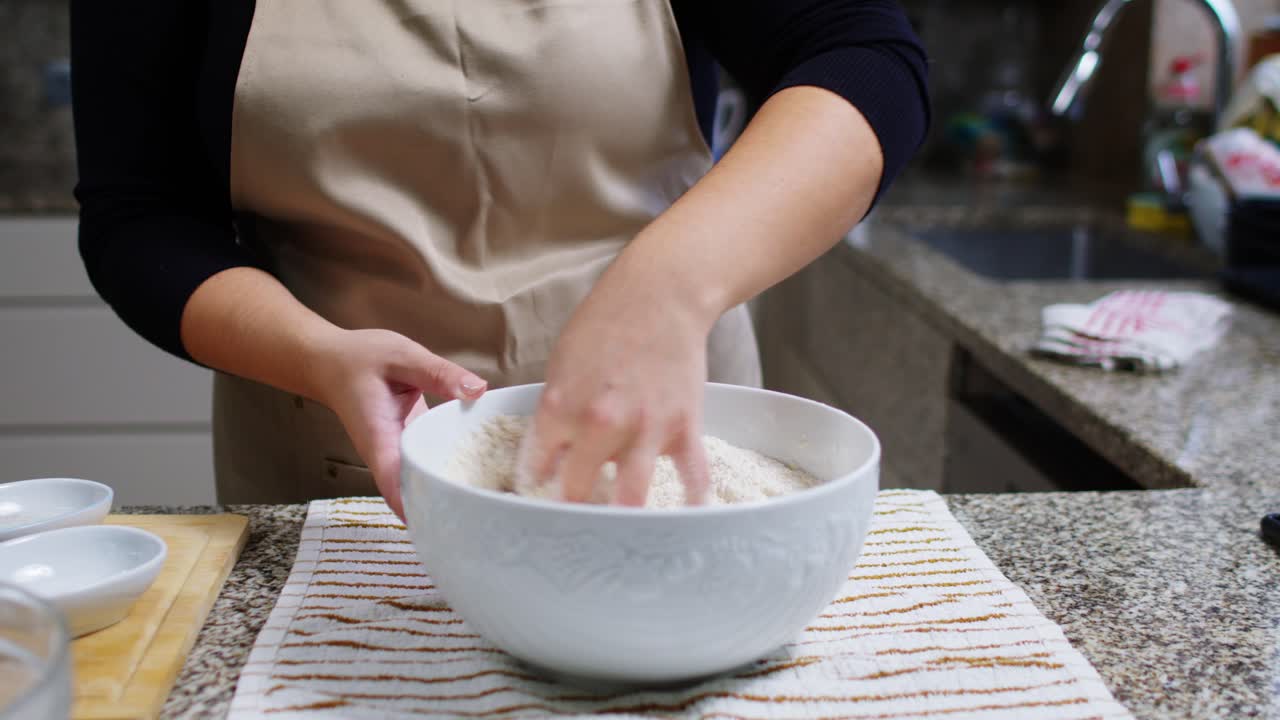Hand mixing white flour inside a ceramic bowl for baking in a cozy kitchen.