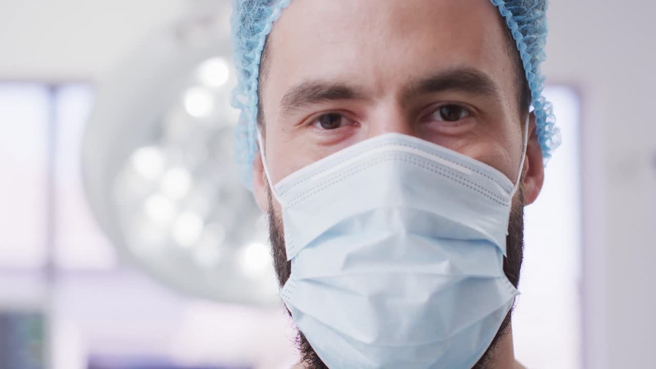 retrato de video de un cirujano caucásico con gorra quirúrgica y máscara facial en el teatro, espacio de copia