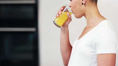 pregnant woman drinking orange juice in the kitchen