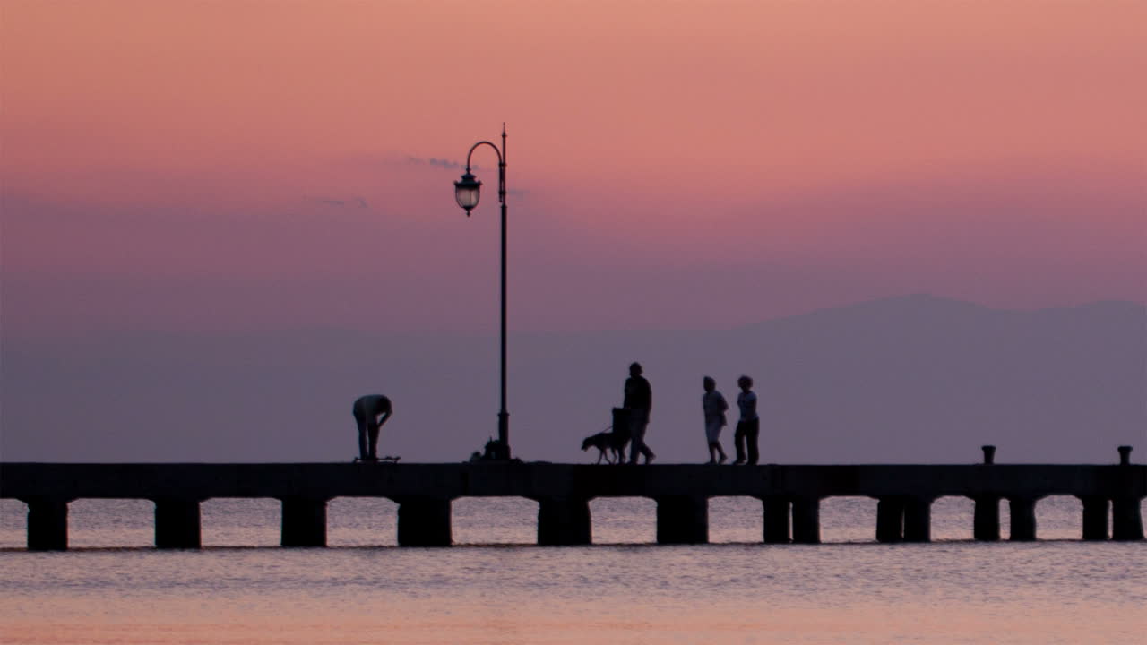 Family walking their dog on a pier at sunset