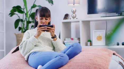 Teenager-using-a-phone-while-relaxing-on-a-bean